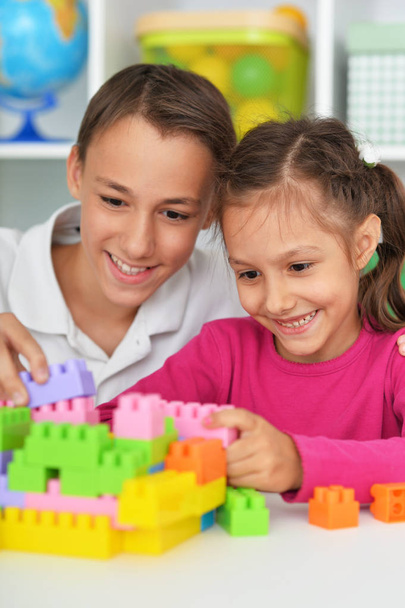 Brother and sister playing with colorful plastic blocks together - 写真・画像
