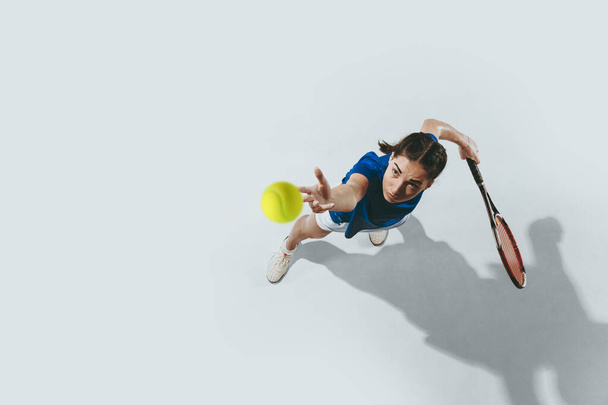 Young woman in blue shirt playing tennis. Youth, flexibility, power and energy. - Foto, afbeelding