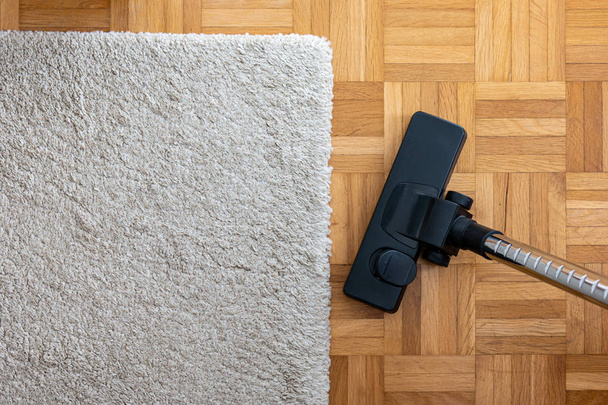 Stofzuiger verlenging op een gelamineerde houten vloer naast een g - Foto, afbeelding