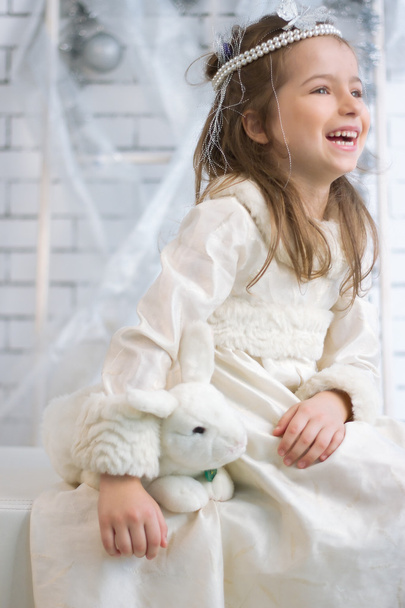 Girl in winter holiday dress with toy rabbit - 写真・画像