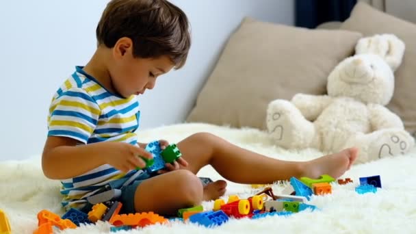 Slow Motion Aziatische jongen spelen met kleurrijke bouwkunst stof blokken op wit bed thuis . - Video