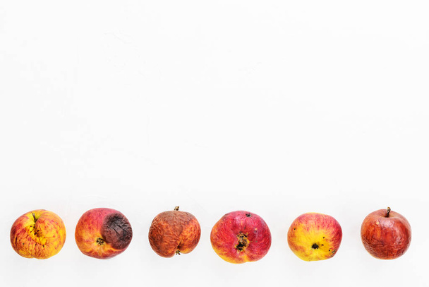 Lelijke rotte appels op een witte achtergrond. Horizontale oriëntatie, kopieerruimte, vlakke lay. - Foto, afbeelding