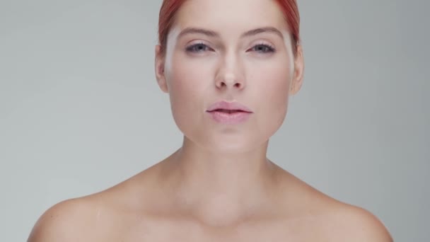 Studio portrait of young, beautiful and natural redhead woman applying skin care cream. Face lifting, cosmetics and make-up. - Imágenes, Vídeo
