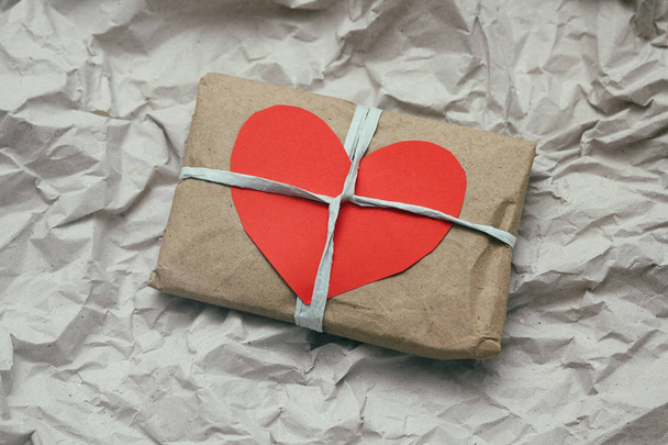 Soft pouch wrapped in craft paper and tie cord. Big red carton heart post card. Crumpled paper background texture. Delivery service. Online shopping. - Φωτογραφία, εικόνα