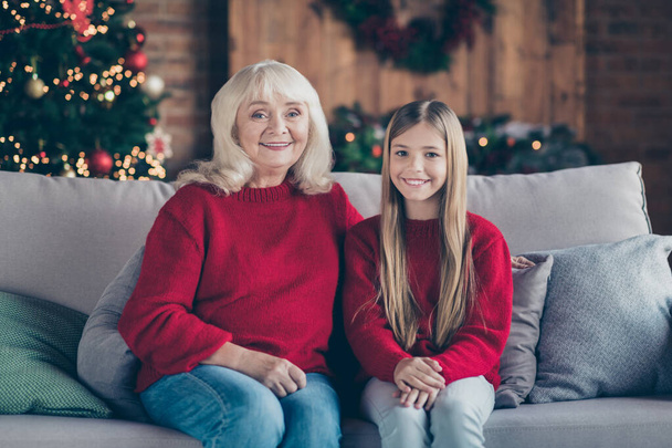 Portrait of nice attractive lovely charming cheerful cheery granny grandchild sitting on divan spending festal eve noel holiday at industrial loft style interior house indoors - Foto, Imagen