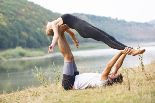 guy and girl doing yoga on the river bank - Foto, imagen