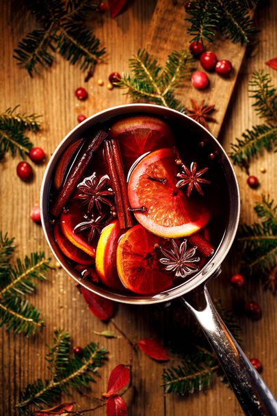 Natale vin brulè rosso con l'aggiunta di spezie e agrumi in una pentola su un tavolo di legno rustico, vista dall'alto. Vaso di vin brulè, bevanda natalizia tradizionale
. - Foto, immagini