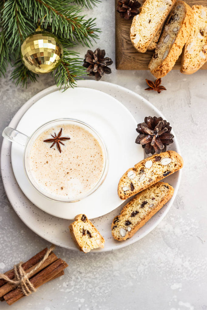 Eggnog. Christmas milk cocktail with cinnamon and anise, served in glass mug with biscotti, winter spices, fir branches and cones. - Photo, image