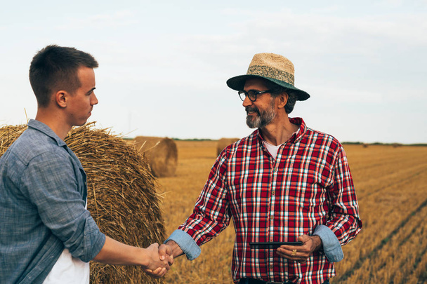 workers handshaking on wheat field - Foto, imagen