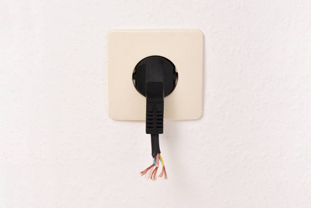 The cut-off cable from the plug. Dangerous plug in the socket. - Photo, Image