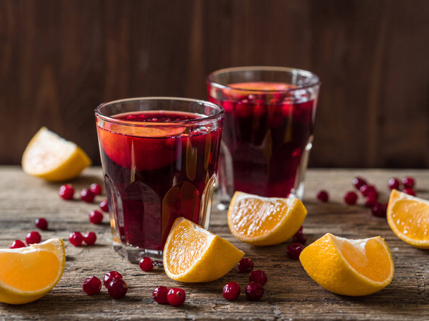 Traditional Christmas drink. Christmas hot mulled wine with oranges, cranberries and spices on a wooden table - Fotografie, Obrázek