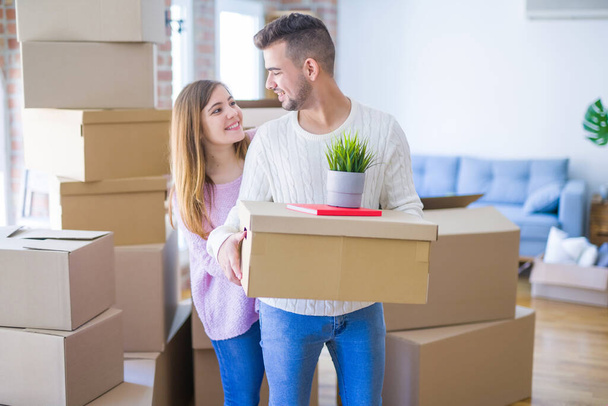 Молодая красивая влюбленная пара переезжает в новый дом, держа картонные коробки очень счастливой и веселой для новой квартиры
 - Фото, изображение