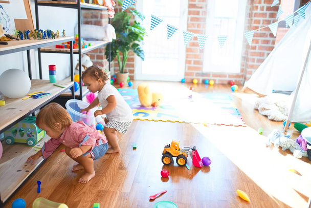Adoráveis crianças brincando em torno de muitos brinquedos no jardim de infância
 - Foto, Imagem
