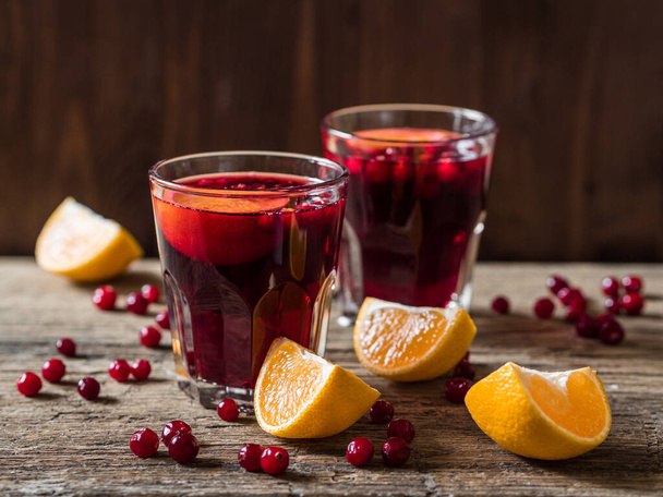 Traditional Christmas drink. Christmas hot mulled wine with oranges, cranberries and spices on a wooden table - Fotografie, Obrázek