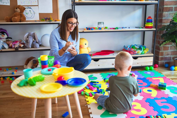 Nuori terapeutti nainen puhuu lapsen, ohjaajan ja käyttäytymisen kanssa oikaisu toimistossa lelujen ympärillä
 - Valokuva, kuva