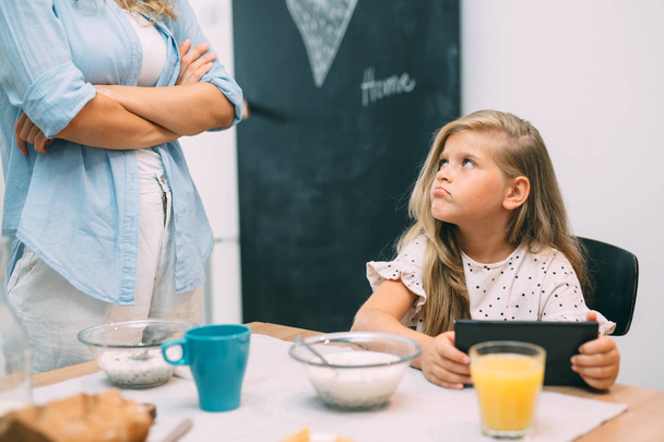 mother arguing with daughter about using tablet at breakfast time  - Foto, afbeelding