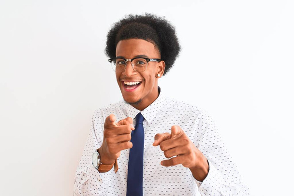Joven empresario afroamericano con corbata y gafas sobre fondo blanco aislado señalando los dedos a la cámara con cara alegre y divertida. Buena energía y vibraciones
. - Foto, imagen