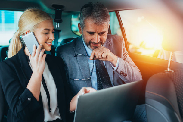 business colleagues using laptop sitting backseat of car - Photo, image