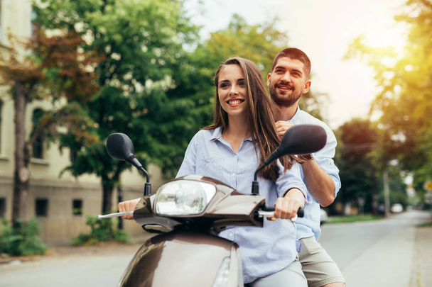 Young happy couple driving on motorbike outdoor with bright sunshine - Fotografie, Obrázek