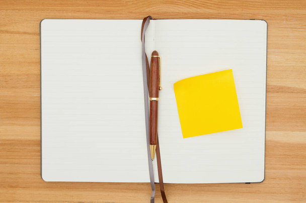 Prázdný deník s perem a žlutou lepkavou poznámkou na dřevěném stole - Fotografie, Obrázek