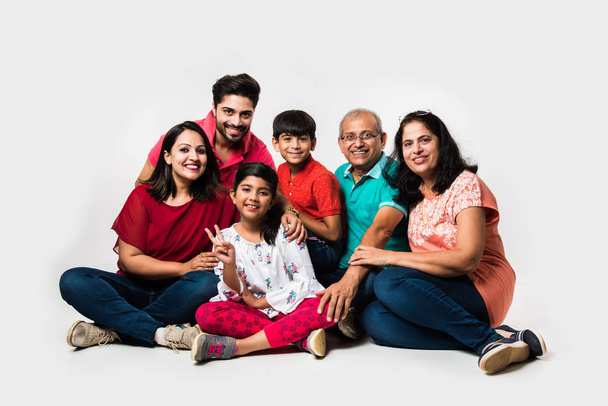 Enfants indiens avec parents / grands-parents, assis isolé sur fond blanc, plan studio
 - Photo, image