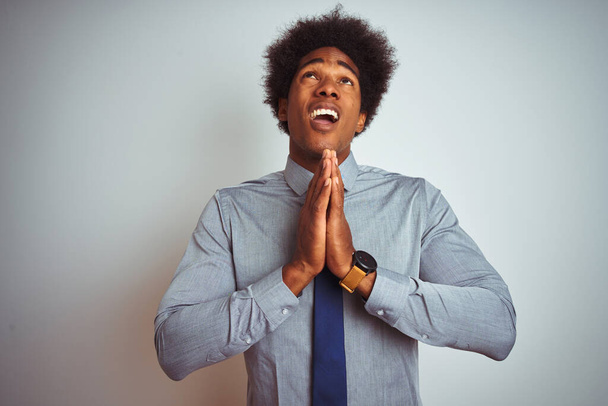 Amerikkalainen liikemies afro hiukset yllään paita ja solmio yli eristetty valkoinen tausta kerjääminen ja rukoilee kädet yhdessä toivon ilme kasvot hyvin emotionaalinen ja huolissaan. Pyytää anteeksiantoa. Uskonnon käsite
. - Valokuva, kuva