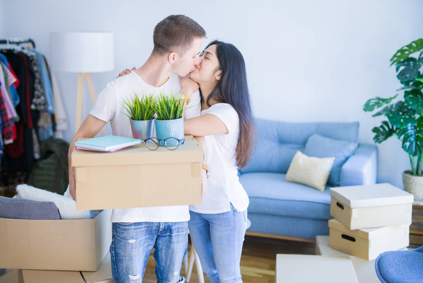 Young beautiful couple at new home around cardboard boxes - Fotoğraf, Görsel
