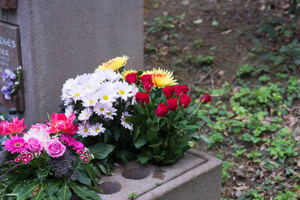 mnoho barevných květin vedle hrobu urny - Fotografie, Obrázek