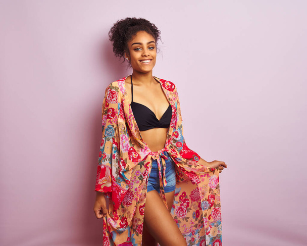 Young beautiful african american woman on vacation standing wearing bikini and colorful caftan - Photo, image