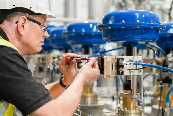 engineer checks an pneumatic valve with a screwdriver - Photo, Image