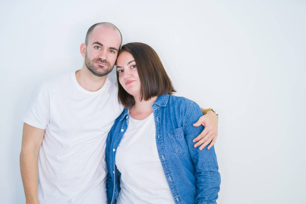 Young couple together over white isolated background with serious expression on face. Simple and natural looking at the camera. - Foto, Bild