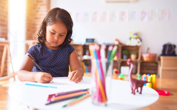 Красивая малышка рисует милые рисунки цветными карандашами в детском саду
 - Фото, изображение