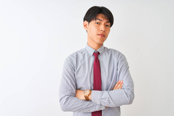 Китайский бизнесмен в элегантном галстуке стоит на изолированном белом фоне скептически и нервно, неодобрительное выражение лица со скрещенными руками. Отрицательное лицо
. - Фото, изображение