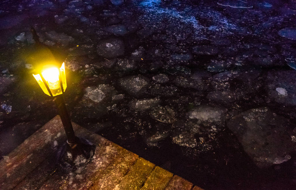 malé pouliční světlo na okraji mola v zimním jezeře s plovoucím ledem - Fotografie, Obrázek