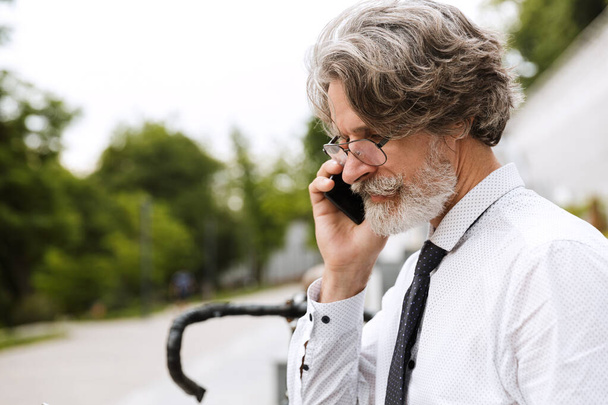 Photo of serous mature businessman talking on cellphone - Fotografie, Obrázek