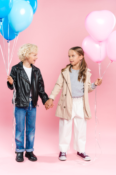 smiling kids holding balloons and holding hands on pink background  - Zdjęcie, obraz