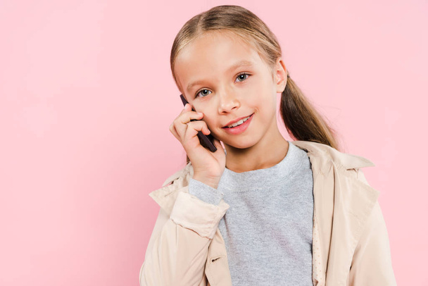 smiling and cute kid talking on smartphone isolated on pink - Valokuva, kuva