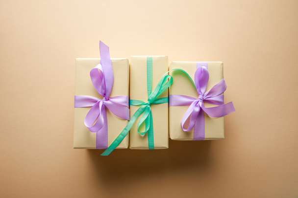 top view of gift boxes with violet and green ribbons on beige background - Valokuva, kuva