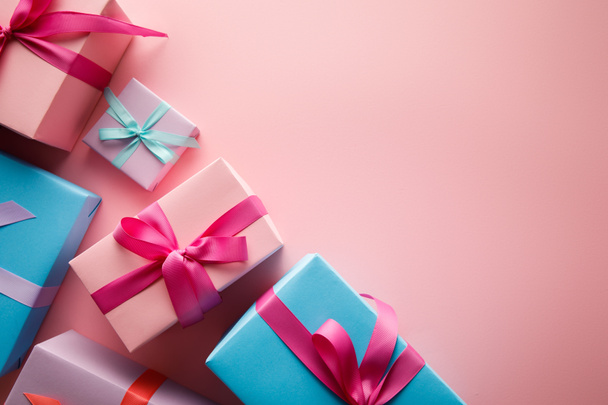 top view of colorful gift boxes with satin ribbons on pink background - Фото, зображення