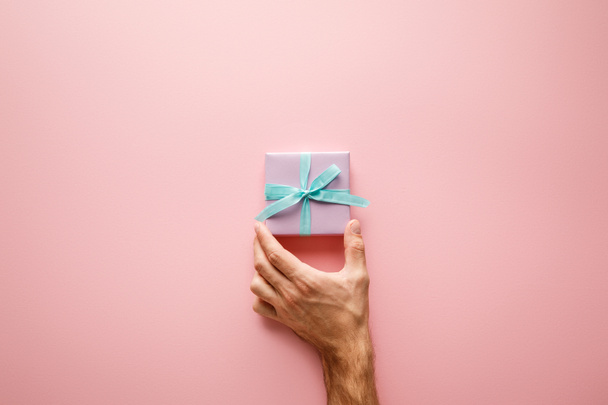 vágott kilátás férfi gazdaság ibolya kis ajándék doboz kék szatén szalag rózsaszín háttér - Fotó, kép