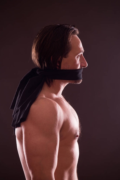 Profile view of shirtless handsome man with black band around his mouth - Фото, зображення