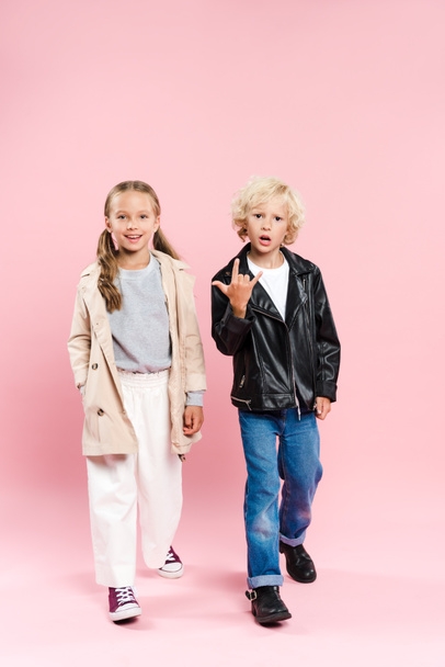 kids smiling and showing rock sign on pink background  - 写真・画像