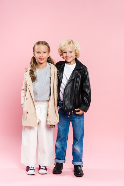 smiling kids hugging and looking at camera on pink background  - Фото, изображение