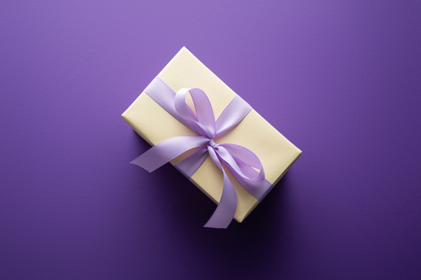 top view of gift box with violet ribbon on purple background - Foto, imagen