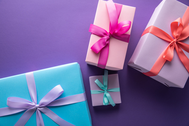 top view of colorful gift boxes with ribbons and bows on purple background with copy space - Fotó, kép