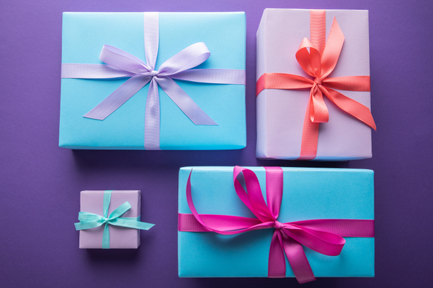 vue du dessus des boîtes-cadeaux colorées avec des rubans et des arcs sur fond violet
 - Photo, image