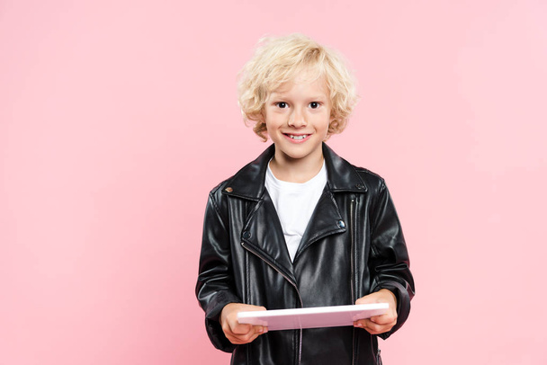 smiling kid holding digital tablet and looking at camera isolated on pink - Fotoğraf, Görsel