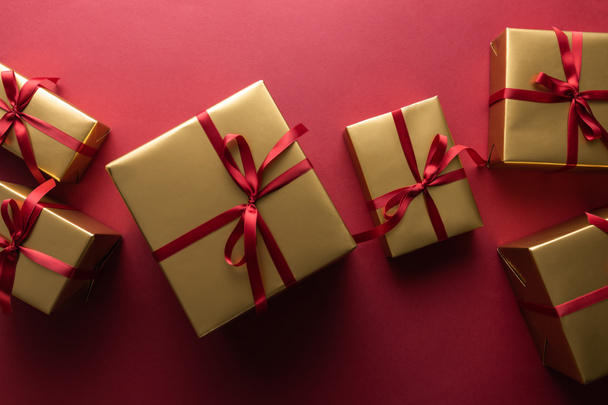 top view of golden gift boxes with ribbons on red background - Foto, Imagem
