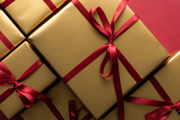 top view of golden gift boxes with ribbons on red background - Foto, Imagem