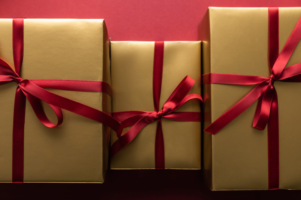 flat lay with golden gift boxes with ribbons on red background - Foto, immagini